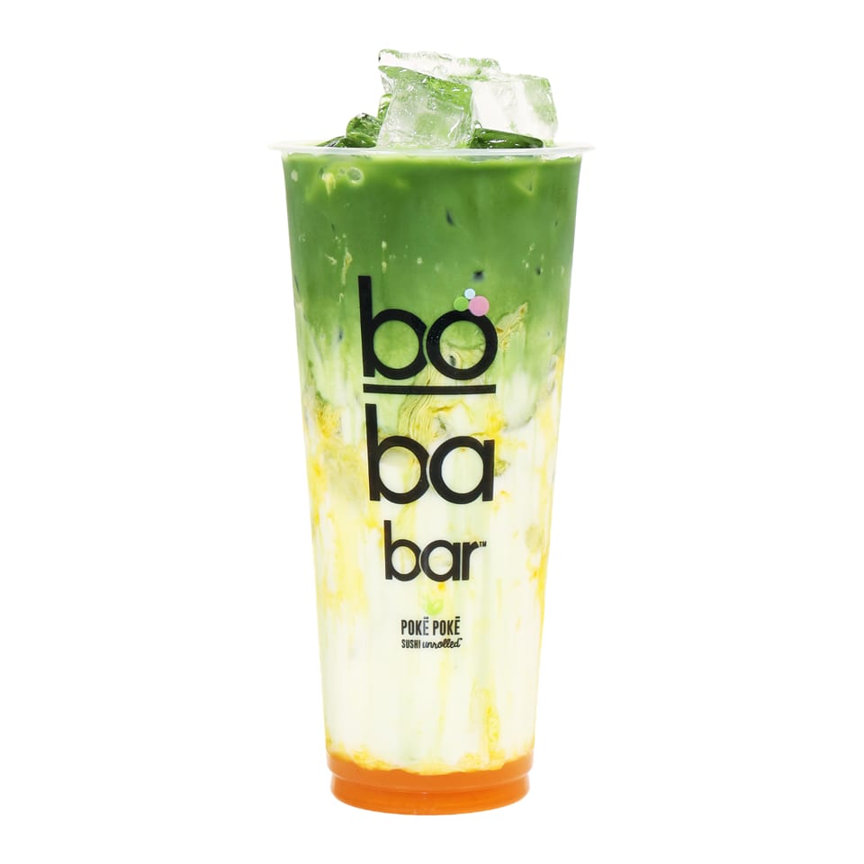 A vibrant green matcha drink with white and yellow layers, topped with ice, from Boba Bar.